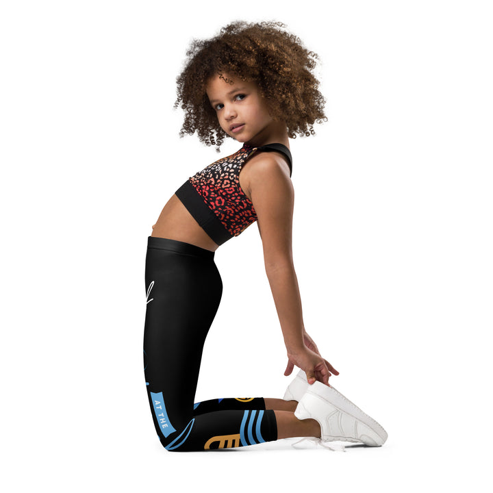 Aqua Kitty Winner Girls Leggings, black background with a blue and yellow swimmer cat wearing a diving mask and swim cap on one leg, golden medal and pool slippers below, "at the pool" text with water drop, and pool water with ladder on the other leg, left side view kneeling on model