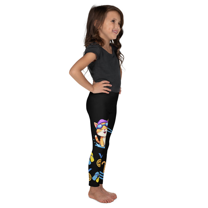 Aqua Kitty Winner Girls Leggings, black background with a blue and yellow swimmer cat wearing a diving mask and swim cap on one leg, golden medal and pool slippers below, "at the pool" text with water drop, and pool water with ladder on the other leg, right side view on model