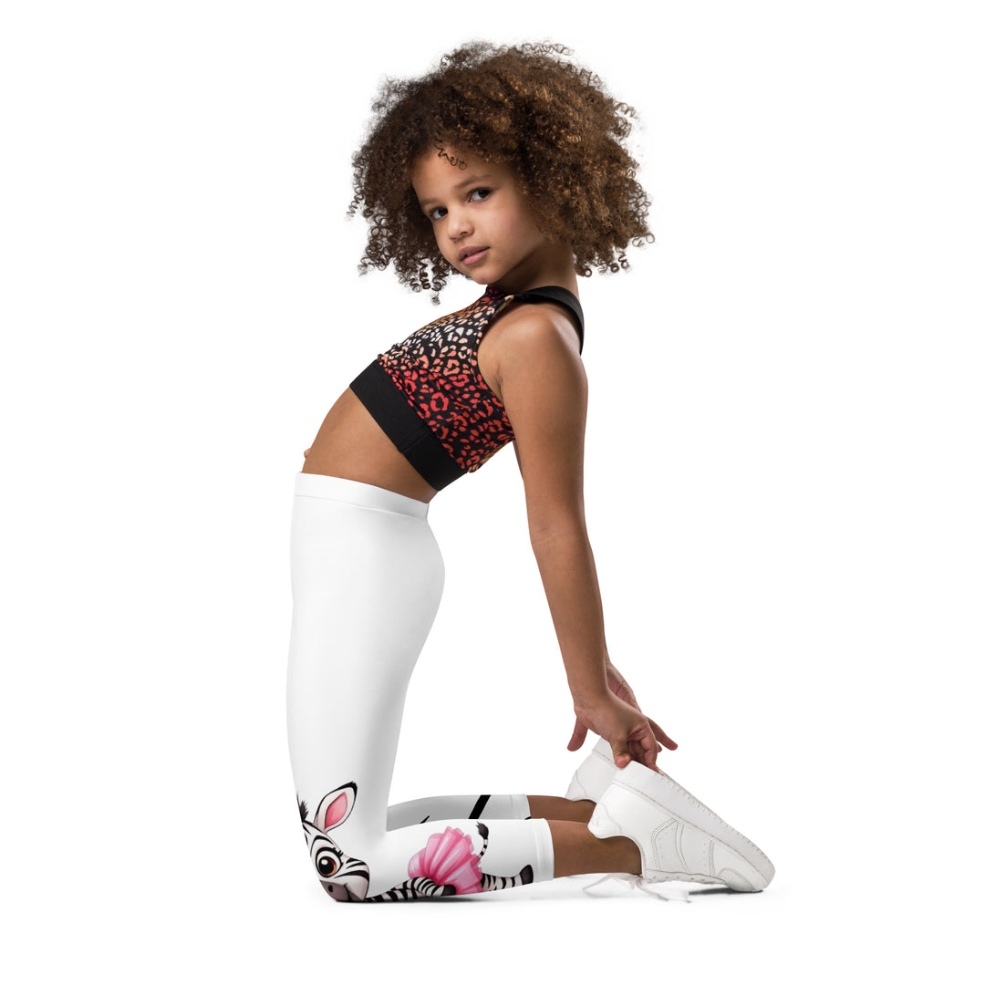 Ballet Black and White Zebra Girls Leggings, white background with a black and white zebra wearing a pink ballet skirt on the lower part of one leg, and black zebra stripes on the lower part of the other leg, left side view kneeling on model