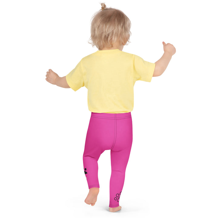 Cat Trace Girls Leggings, pink background with a yellow cat wearing a pink dress at the top of one leg, black paw prints and a black cat nose below, and a black line-drawn cat with black and cream paw prints on the other leg, back pose on model