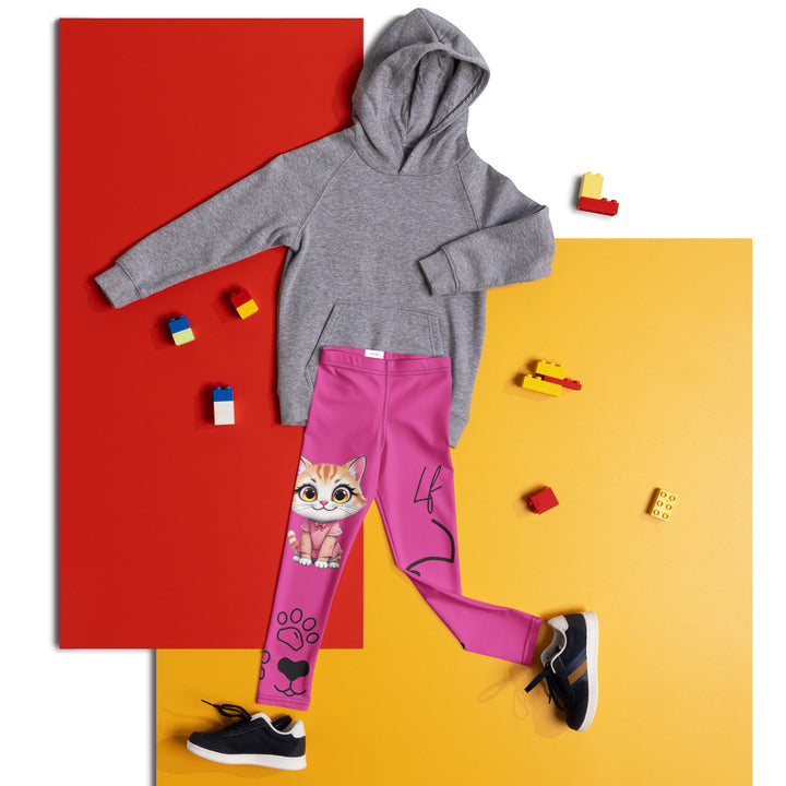 Cat Trace Girls Leggings, pink background with a yellow cat wearing a pink dress at the top of one leg, black paw prints and a black cat nose below, and a black line-drawn cat with black and cream paw prints on the other leg, front view laid flat on floor