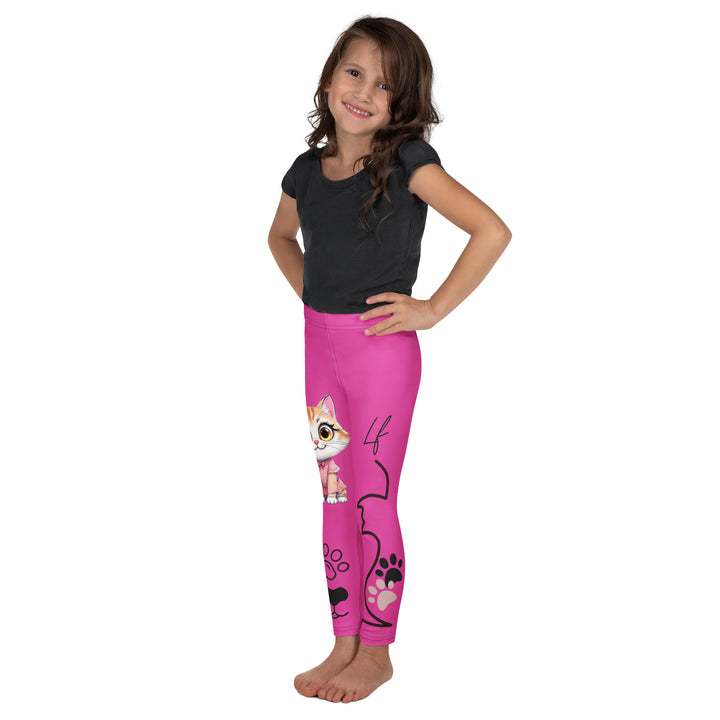 Cat Trace Girls Leggings, pink background with a yellow cat wearing a pink dress at the top of one leg, black paw prints and a black cat nose below, and a black line-drawn cat with black and cream paw prints on the other leg, left side view on model