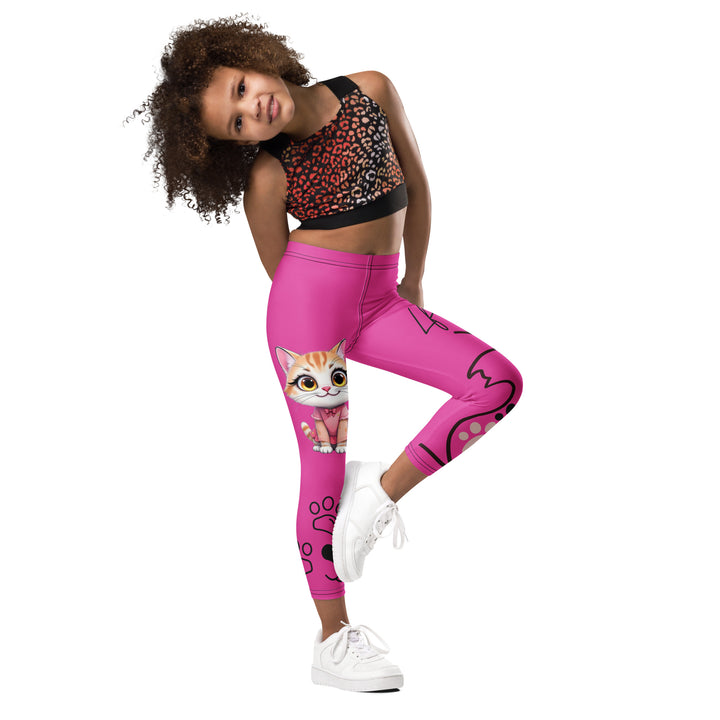  Cat Trace Girls Leggings, pink background with a yellow cat wearing a pink dress at the top of one leg, black paw prints and a black cat nose below, and a black line-drawn cat with black and cream paw prints on the other leg, side view with one leg lifted and bent on model