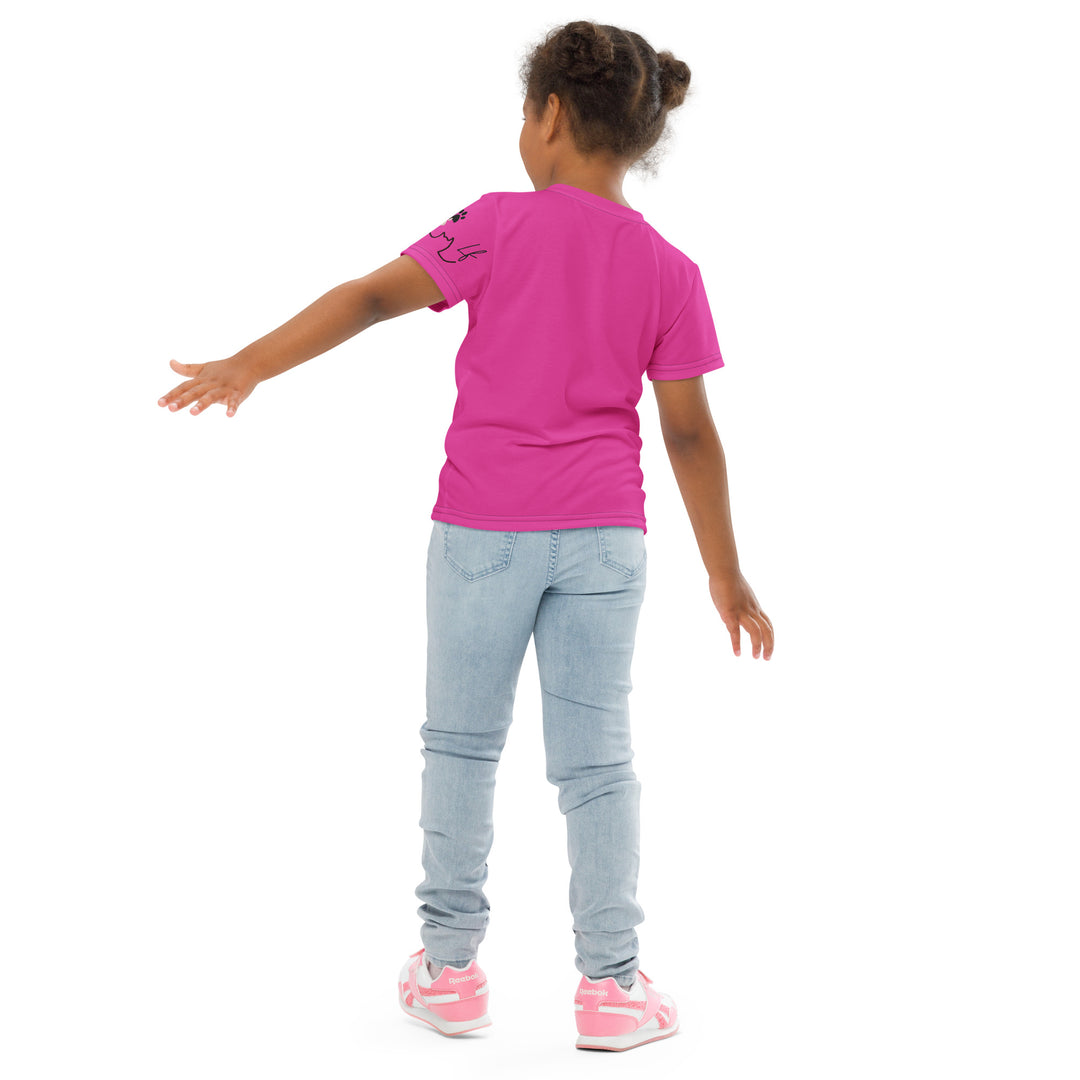 Cat Trace Girls T-shirt, pink background with a yellow cat sitting and wearing a light pink dress, with big eyes, long eyelashes, and a smiling expression on the front, and a black line-drawn cat with one black paw and one cream paw on the left sleeve, back pose on model