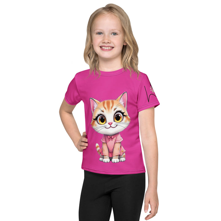 Cat Trace Girls T-shirt, pink background with a yellow cat sitting and wearing a light pink dress, with big eyes, long eyelashes, and a smiling expression on the front, and a black line-drawn cat with one black paw and one cream paw on the left sleeve, front view on model