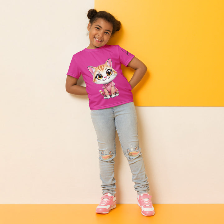 Cat Trace Girls T-shirt, pink background with a yellow cat sitting and wearing a light pink dress, with big eyes, long eyelashes, and a smiling expression on the front, and a black line-drawn cat with one black paw and one cream paw on the left sleeve, relaxed front pose on model
