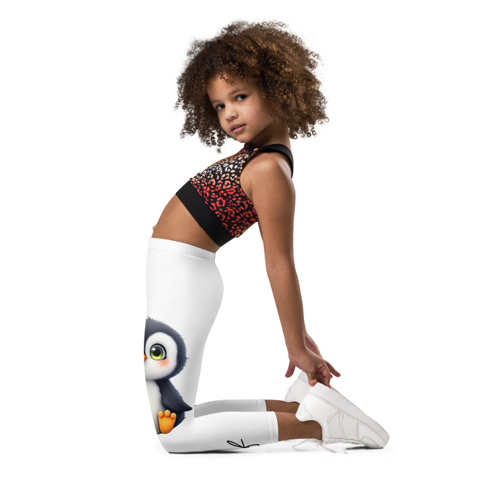 Chilly Penguin Girls Leggings, white background with a black and white small penguin sitting with green eyes on one leg, and a black and white iceberg with a wooden snow sign that says "NORTH POLE" on the other leg, left side view kneeling on model