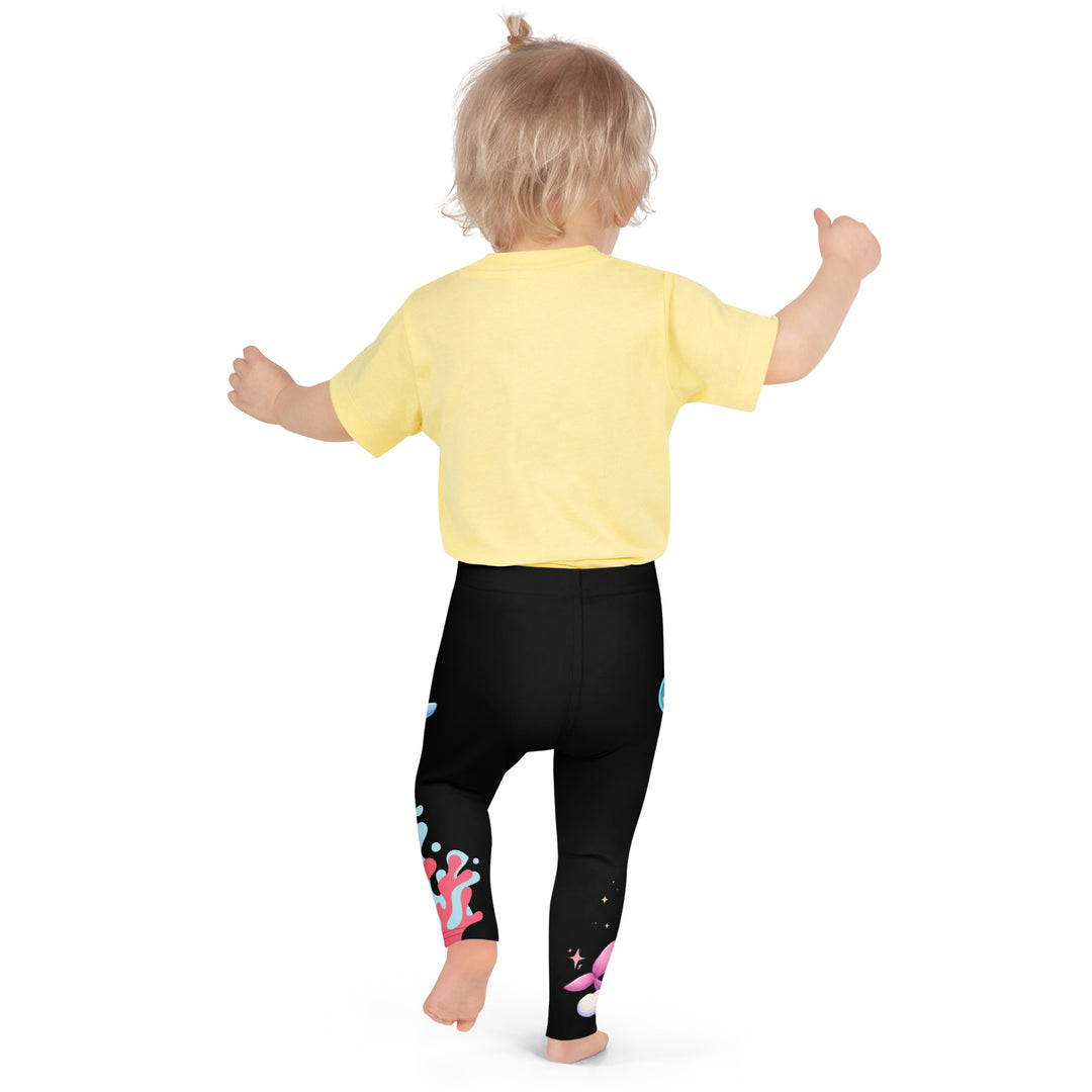  Coral Dolphin Girls Leggings, black background with a pink baby dolphin lying on a white cloud at the bottom of one leg and blue sea bubbles above, and a blue baby dolphin on the upper part of the other leg with pink and blue coral details at the bottom, back pose on model