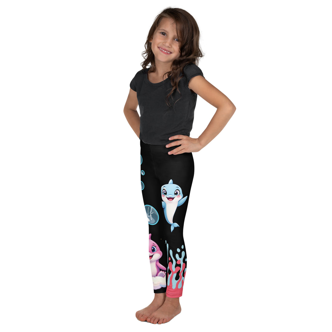 Coral Dolphin Girls Leggings, black background with a pink baby dolphin lying on a white cloud at the bottom of one leg and blue sea bubbles above, and a blue baby dolphin on the upper part of the other leg with pink and blue coral details at the bottom, left side view on model