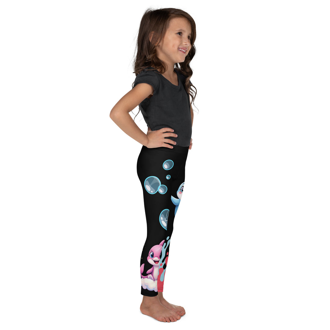  Coral Dolphin Girls Leggings, black background with a pink baby dolphin lying on a white cloud at the bottom of one leg and blue sea bubbles above, and a blue baby dolphin on the upper part of the other leg with pink and blue coral details at the bottom, right side view on model