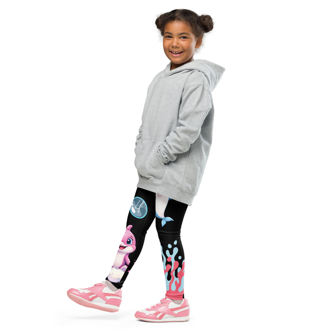 Coral Dolphin Girls Leggings, black background with a pink baby dolphin lying on a white cloud at the bottom of one leg and blue sea bubbles above, and a blue baby dolphin on the upper part of the other leg with pink and blue coral details at the bottom, side view with one leg lifted and extended on model