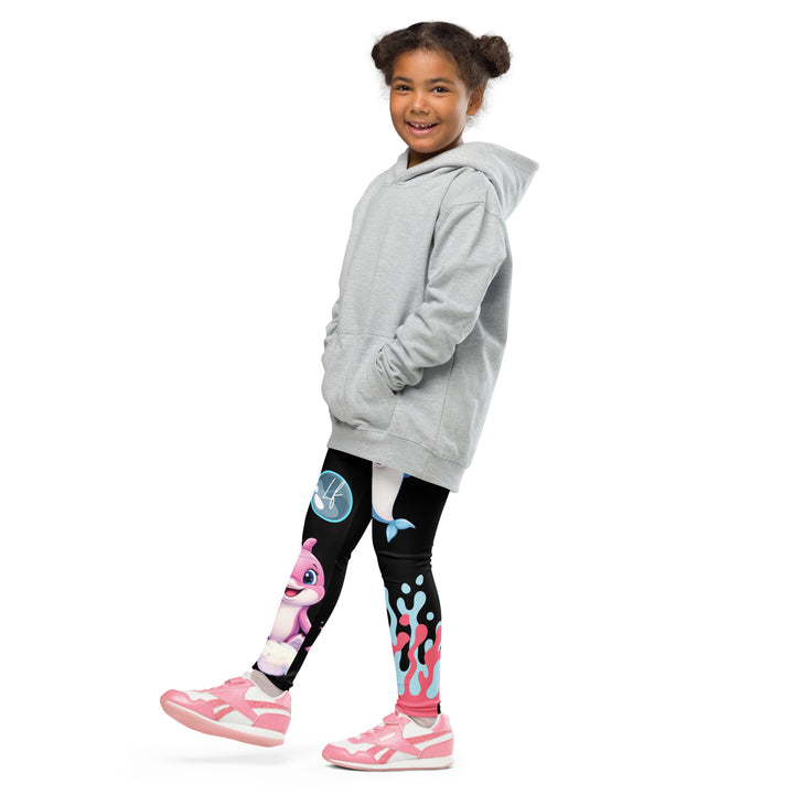 Coral Dolphin Girls Leggings, black background with a pink baby dolphin lying on a white cloud at the bottom of one leg and blue sea bubbles above, and a blue baby dolphin on the upper part of the other leg with pink and blue coral details at the bottom, side view with one leg lifted and extended on model