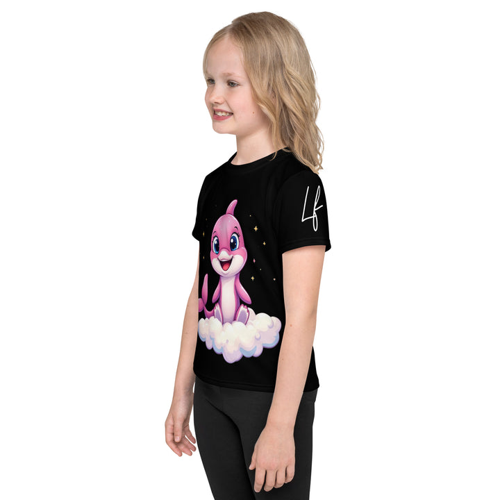 Coral Dolphin Girls T-shirt, black background with a pink baby dolphin sitting on a white cloud surrounded by small sparkling yellow stars, left side view on model