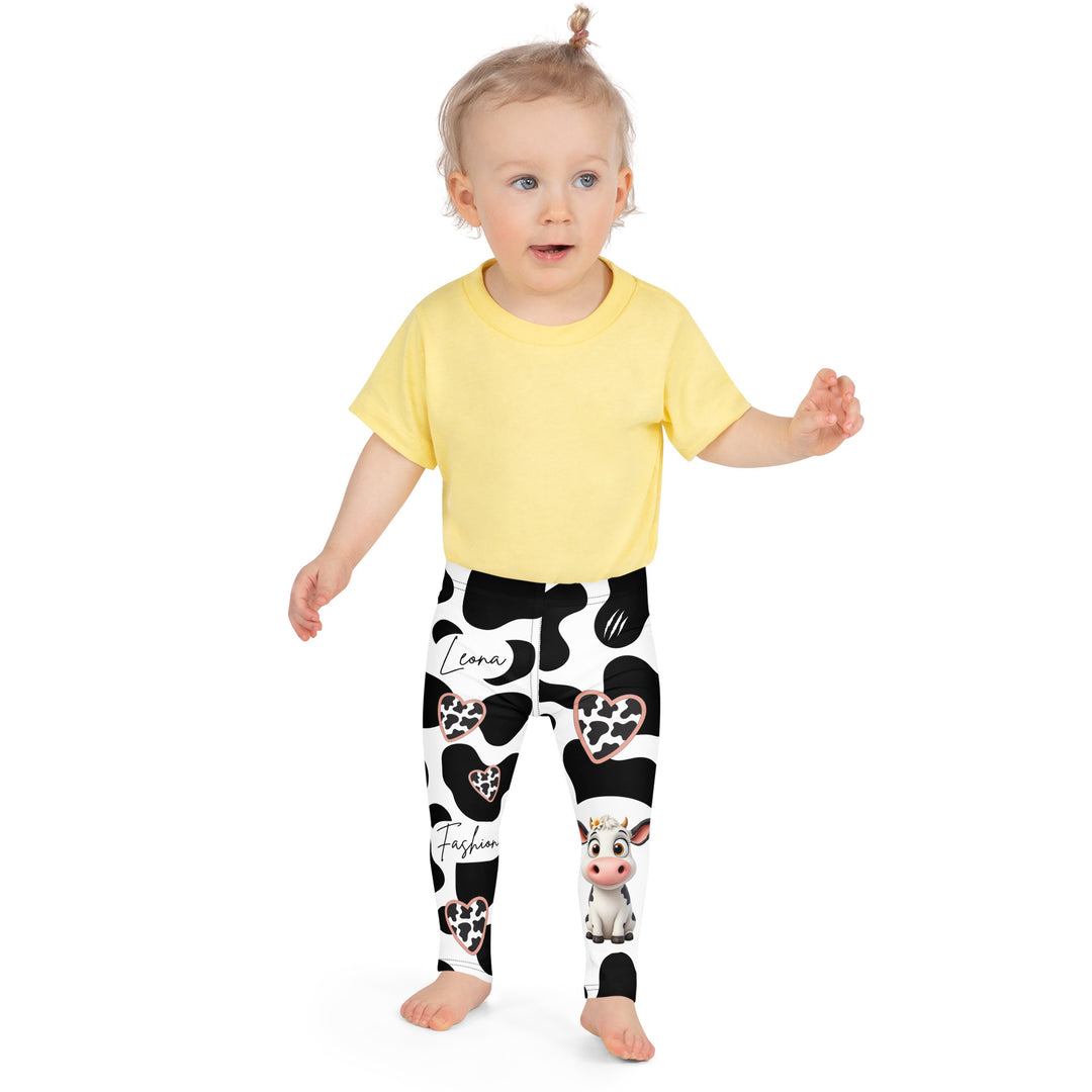  Cowlicious Love Girls Leggings, white background with black cow-like spots and a small black and white cow with a flower in its hair on one leg, front close-up view on model-with a visible 'Leona Fashion' text on the design