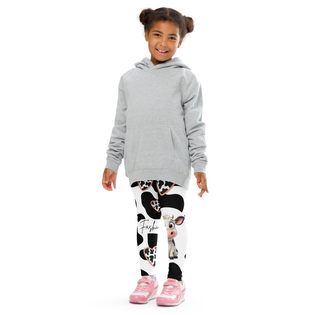 Cowlicious Love Girls Leggings, white background with black cow-like spots and a small black and white cow with a flower in its hair on one leg, front pose with arms at sides on model-with a visible 'Leona Fashion' text on the design