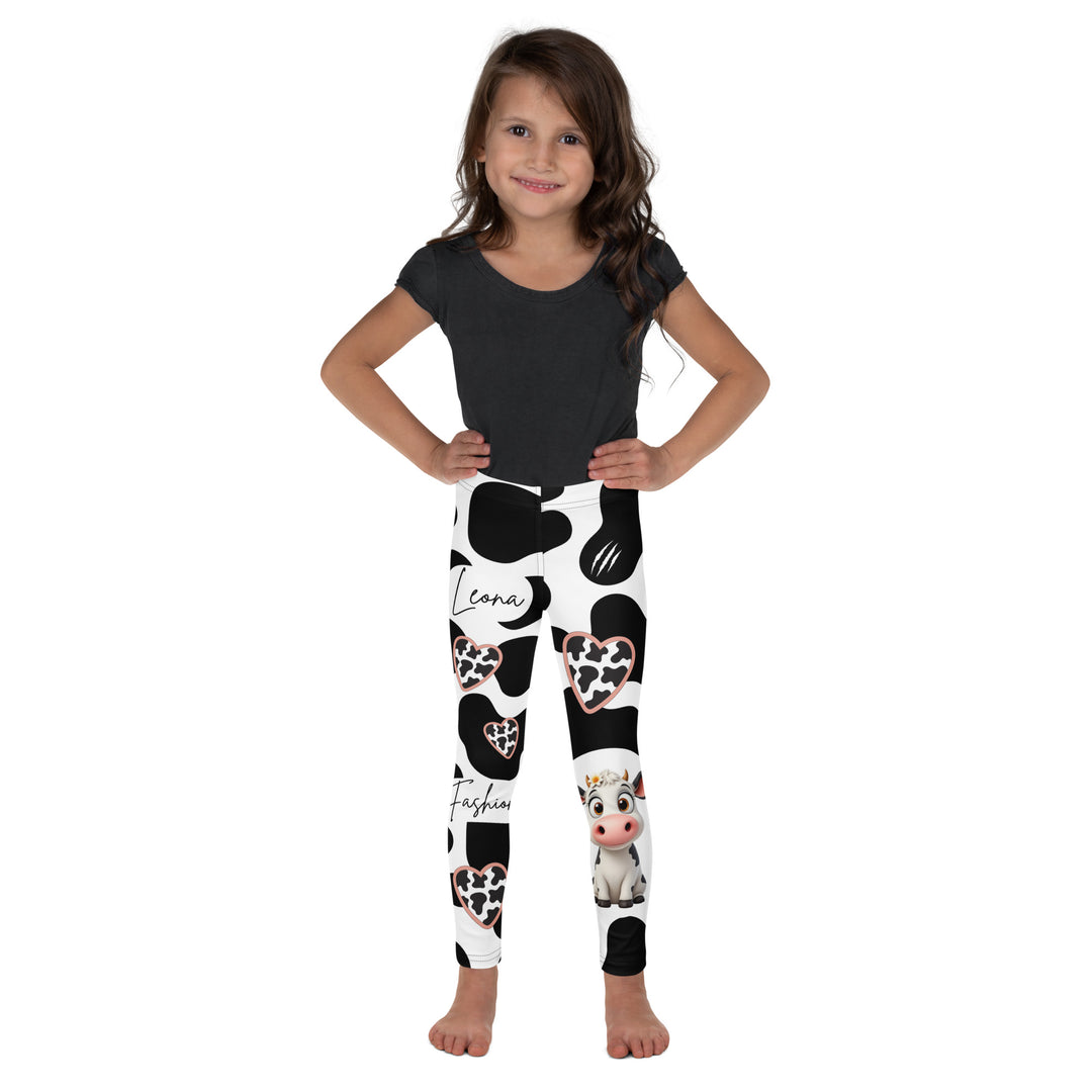 Cowlicious Love Girls Leggings, white background with black cow-like spots and a small black and white cow with a flower in its hair on one leg, front view on model-with a visible 'Leona Fashion' text on the design