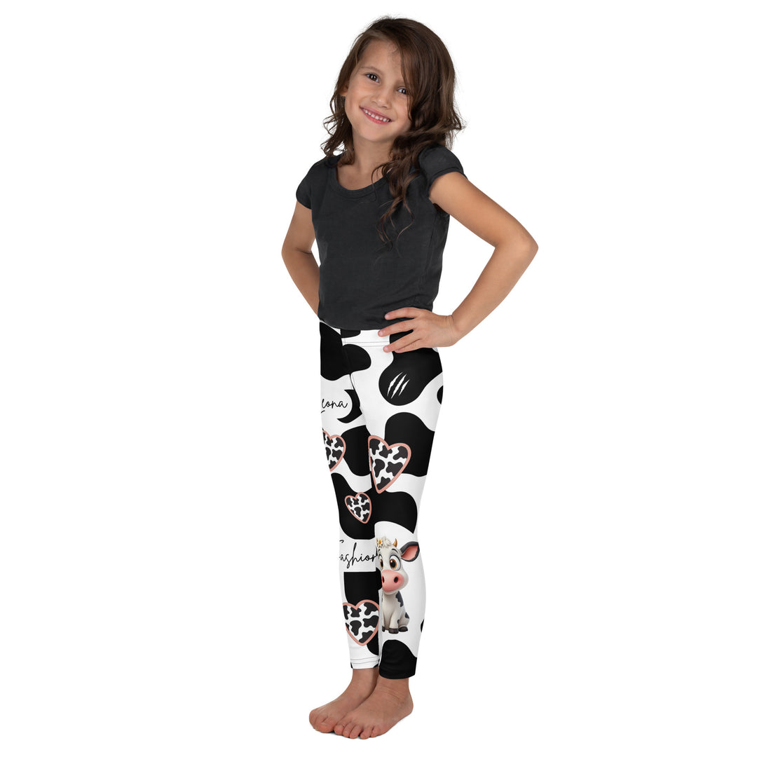  Cowlicious Love Girls Leggings, white background with black cow-like spots and a small black and white cow with a flower in its hair on one leg, left side view on model-with a visible 'Leona Fashion' text on the design