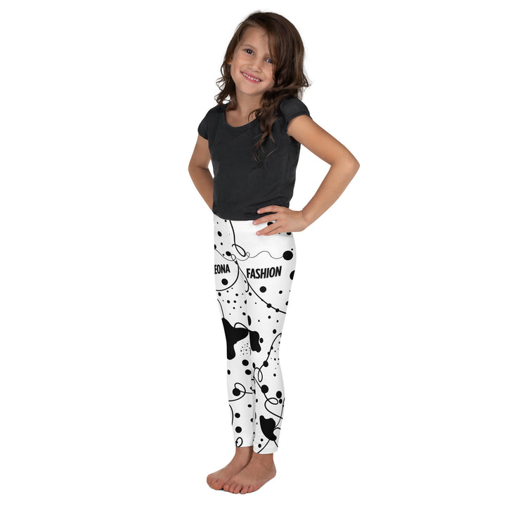 Dot & Line Girls Leggings, white background with black spots, lines, and dots interwoven throughout the design, left side view on model-with a visible 'Leona Fashion' text on the design