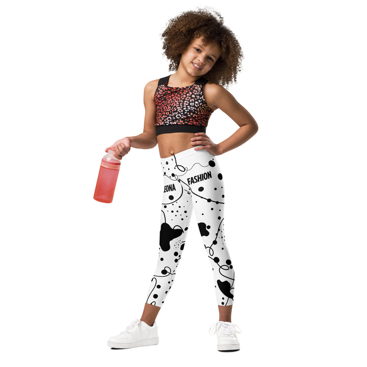 Dot & Line Girls Leggings, white background with black spots, lines, and dots interwoven throughout the design, relaxed front pose on model-with a visible 'Leona Fashion' text on the design