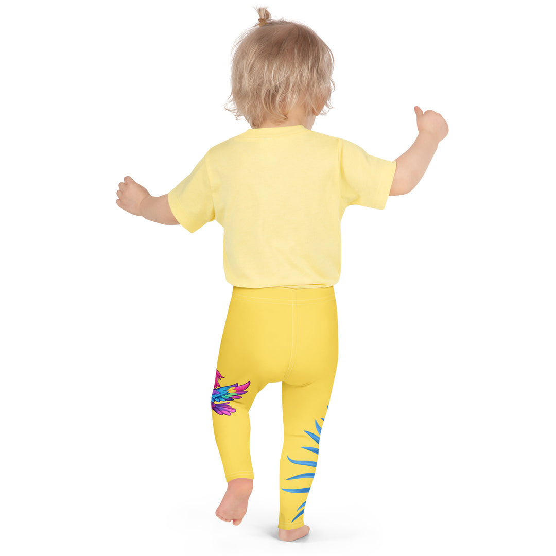 Fly Baby Parrot Girls Leggings, yellow background with a small pink baby parrot with spread wings on one leg, and a large blue tropical leaf with "I CAN DO IT" text in blue and pink letters above it on the other leg, back pose on model
