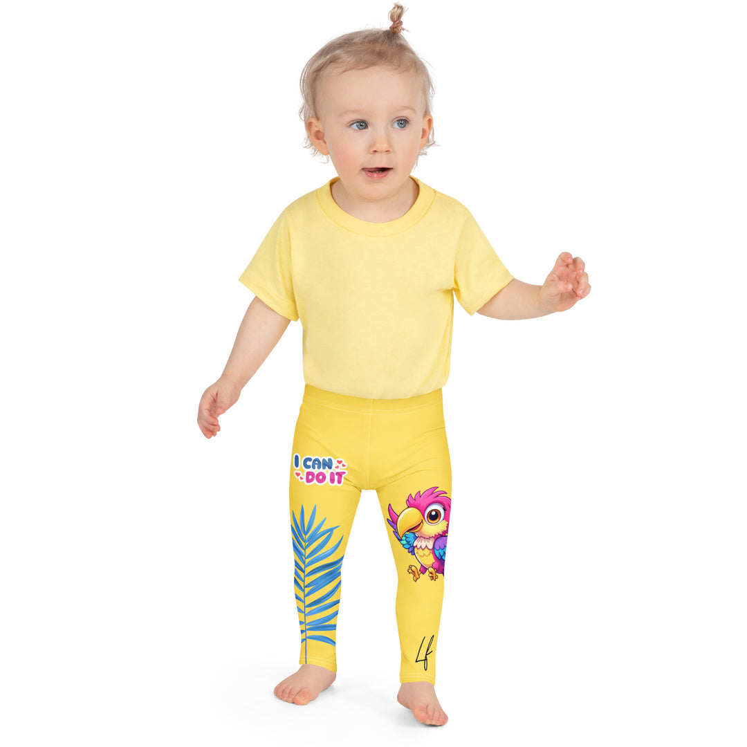 Fly Baby Parrot Girls Leggings, yellow background with a small pink baby parrot with spread wings on one leg, and a large blue tropical leaf with "I CAN DO IT" text in blue and pink letters above it on the other leg, front close-up view on model