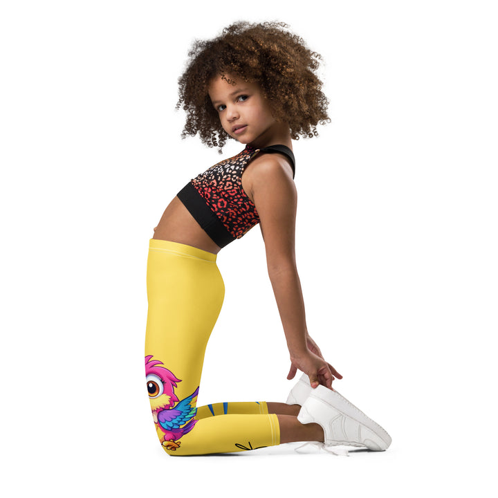 Fly Baby Parrot Girls Leggings, yellow background with a small pink baby parrot with spread wings on one leg, and a large blue tropical leaf with "I CAN DO IT" text in blue and pink letters above it on the other leg, left side view kneeling on model