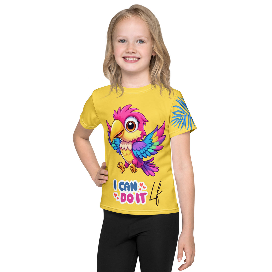 Fly Baby Parrot Girls T-shirt, yellow background with a small pink baby parrot with spread wings on the front, "I CAN DO IT" text in blue and pink letters below, and a blue tropical leaf on the left sleeve, front view on model