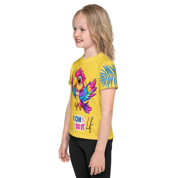 Fly Baby Parrot Girls T-shirt, yellow background with a small pink baby parrot with spread wings on the front, "I CAN DO IT" text in blue and pink letters below, and a blue tropical leaf on the left sleeve, left side view on model