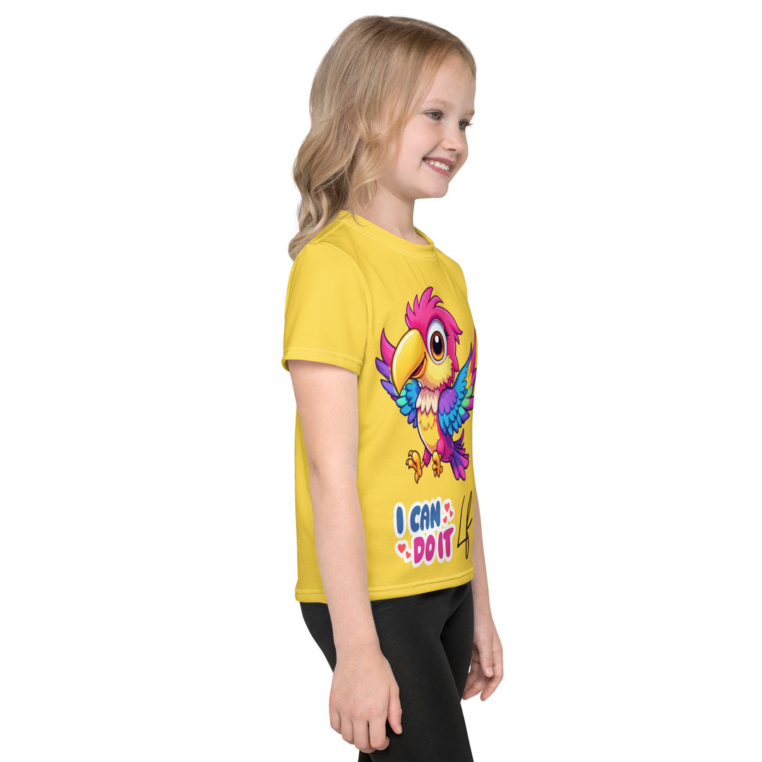 Fly Baby Parrot Girls T-shirt, yellow background with a small pink baby parrot with spread wings on the front, "I CAN DO IT" text in blue and pink letters below, and a blue tropical leaf on the left sleeve, right side view on model