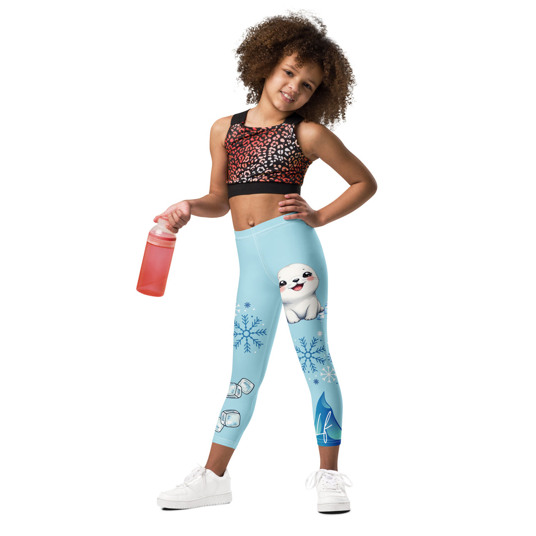 Frosty Seal Girls Leggings, light sky blue background with a white baby seal, blue and white snowflakes, and an ice block on one leg, and blue and white ice cubes with snowflakes on the other leg, relaxed front pose on model