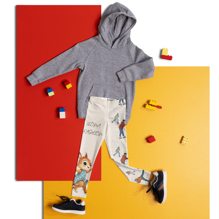 Frosty Twirl Squirrel Girls Leggings, beige background with a brown squirrel ice skating in a blue polka dot dress on one leg, ice trail lines, mountains, and small ice skaters along the other leg, in blue, brown, and orange tones, front view laid flat on floor-with a visible 'Leona Fashion' text on the design