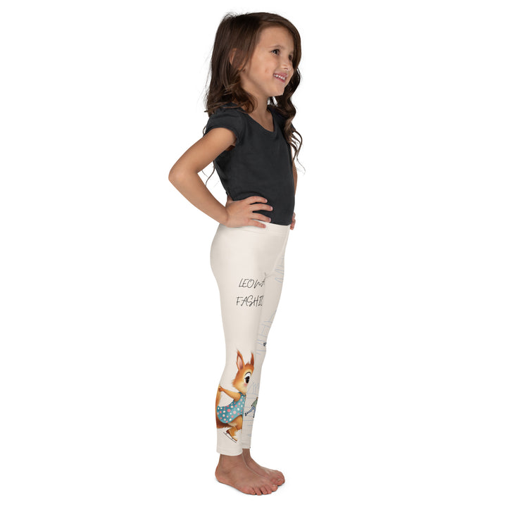 Frosty Twirl Squirrel Girls Leggings, beige background with a brown squirrel ice skating in a blue polka dot dress on one leg, ice trail lines, mountains, and small ice skaters along the other leg, in blue, brown, and orange tones, left side view on model-with a visible 'Leona Fashion' text on the design