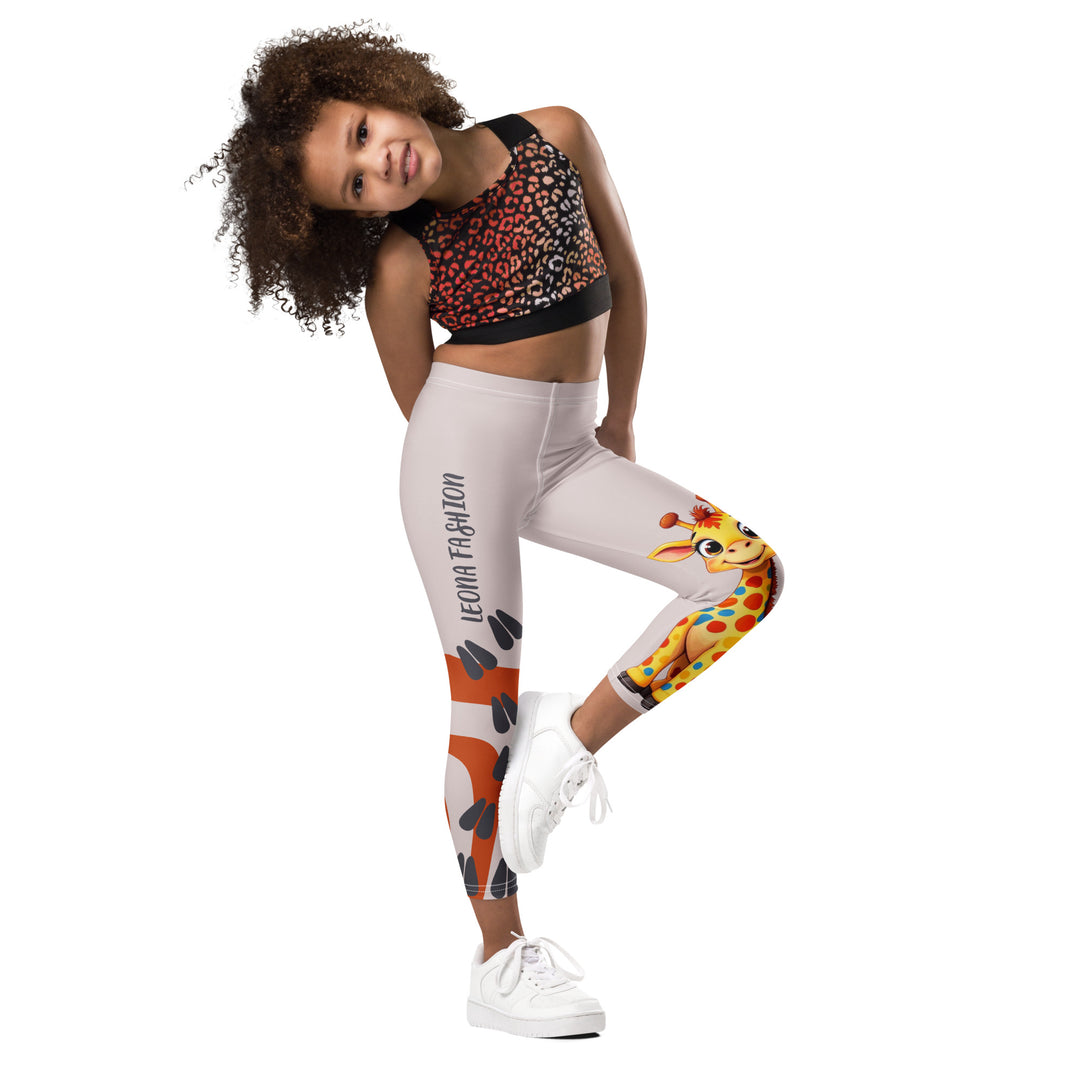 Giraffe Path Girls Leggings, cream background with a yellow giraffe featuring colorful polka dots on one leg, and orange-brown spots with dark gray giraffe footprints on the other leg, both designs starting from above the knee down, side view with one leg lifted and bent on model-with a visible 'Leona Fashion' text on the design