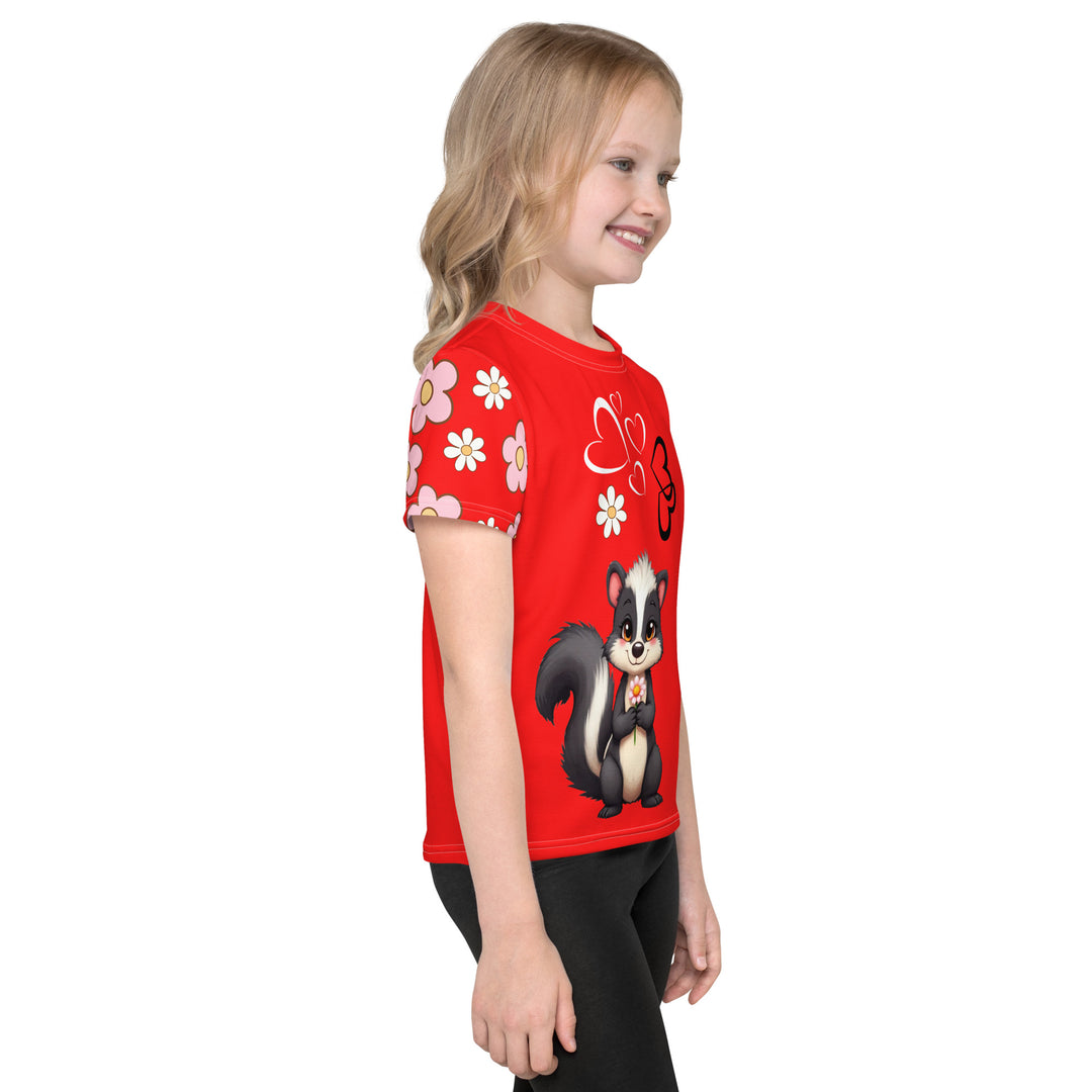 Heart Stinker Girls T-shirt, red background with a black and white skunk holding a white flower in its hand, black and white hearts and a white flower above, and pink-and-white floral details on the right sleeve, right side view on model