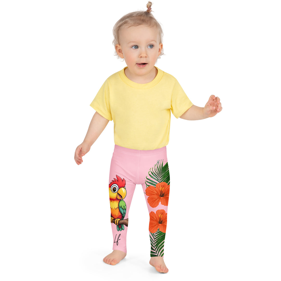 Jungle Parrot Girls Leggings, light pink background with a red, yellow, orange, and green parrot standing on a branch on one leg, and green jungle leaves with two large orange flowers running down the other leg, front close-up view on model
