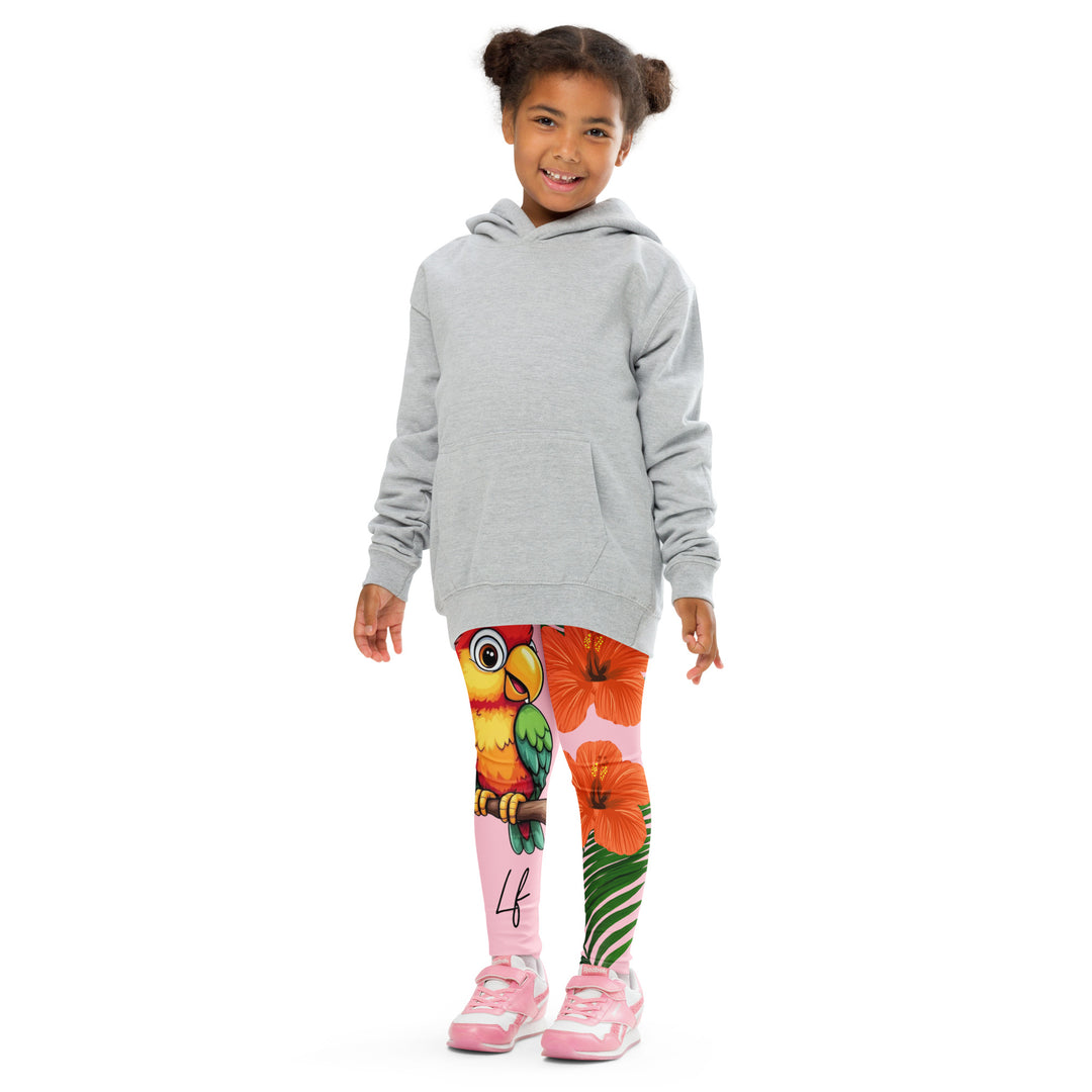 Jungle Parrot Girls Leggings, light pink background with a red, yellow, orange, and green parrot standing on a branch on one leg, and green jungle leaves with two large orange flowers running down the other leg, front pose with arms at sides on model
