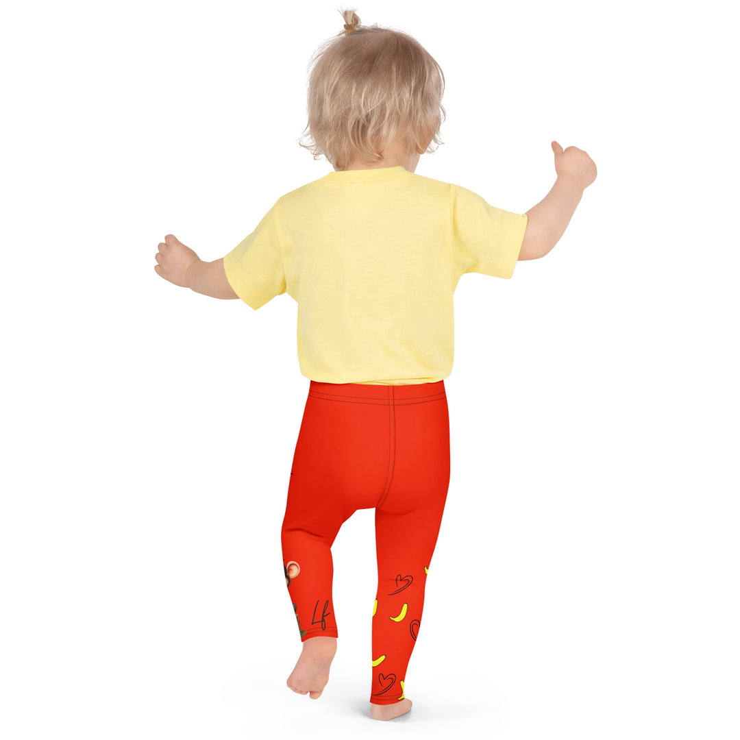 Love Monkey Girls Leggings, red background with a smiling female monkey with big eyes and a pink bow on the head at the top of one leg, yellow bananas with black drawn hearts below, and a winking male monkey wearing a hat sitting on a tree stump near the bottom of the other leg, with the word "LOVE" above, back pose on model
