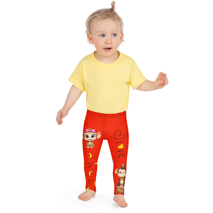  Love Monkey Girls Leggings, red background with a smiling female monkey with big eyes and a pink bow on the head at the top of one leg, yellow bananas with black drawn hearts below, and a winking male monkey wearing a hat sitting on a tree stump near the bottom of the other leg, with the word "LOVE" above, front close-up view on model