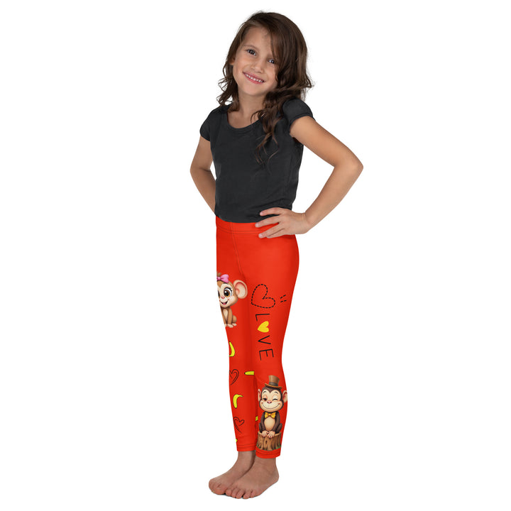 Love Monkey Girls Leggings, red background with a smiling female monkey with big eyes and a pink bow on the head at the top of one leg, yellow bananas with black drawn hearts below, and a winking male monkey wearing a hat sitting on a tree stump near the bottom of the other leg, with the word "LOVE" above, left side view on model