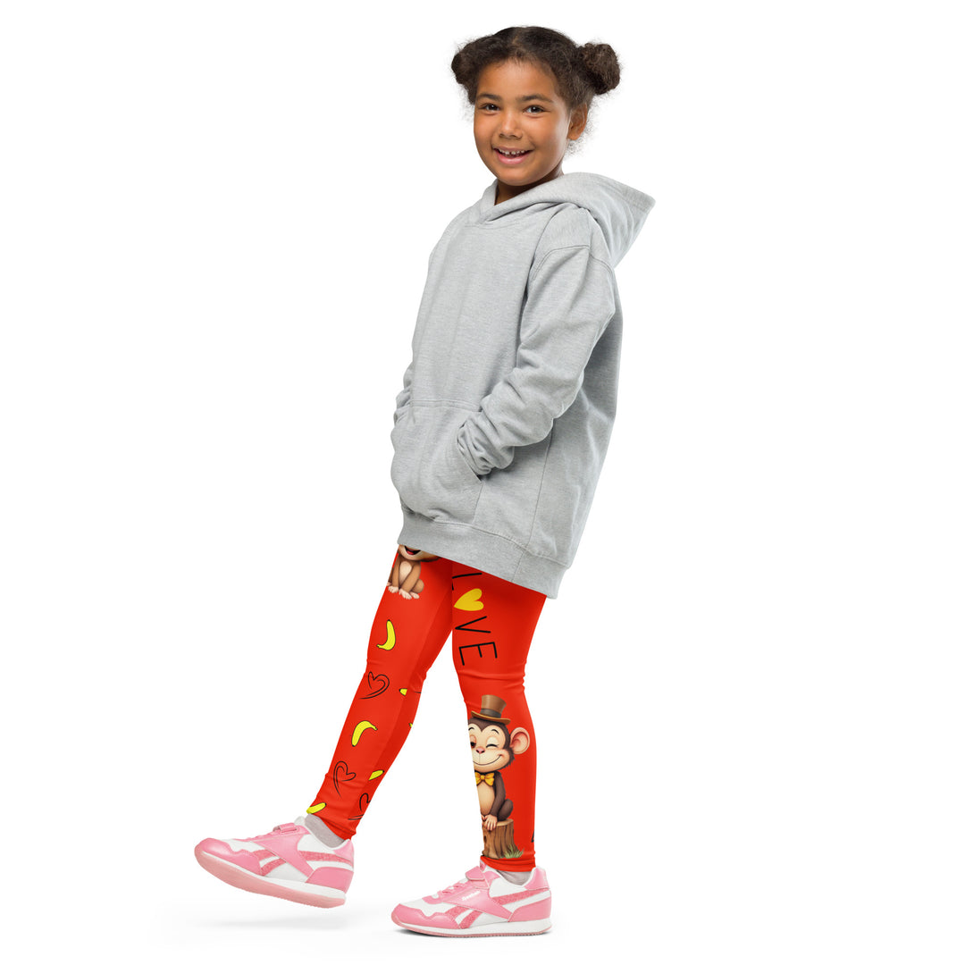 Love Monkey Girls Leggings, red background with a smiling female monkey with big eyes and a pink bow on the head at the top of one leg, yellow bananas with black drawn hearts below, and a winking male monkey wearing a hat sitting on a tree stump near the bottom of the other leg, with the word "LOVE" above, side view with one leg lifted and extended on model