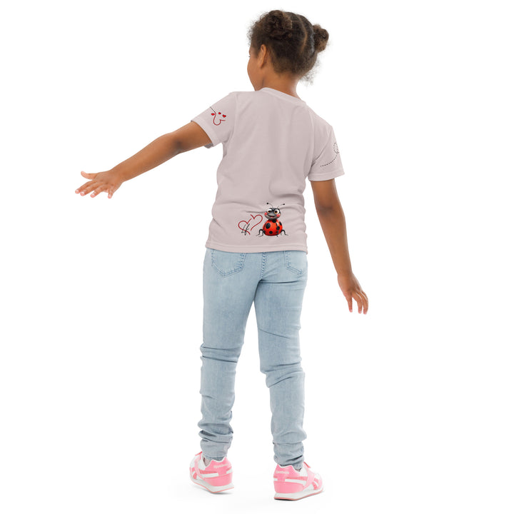  Lovebugs Girls T-shirt, sand-colored background with a smiling female ladybug with big eyes on the front, a happy male ladybug with a heart beside him on the back, and hearts with connecting lines on both sleeves, back pose on model