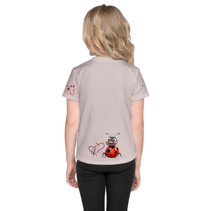  Lovebugs Girls T-shirt, sand-colored background with a smiling female ladybug with big eyes on the front, a happy male ladybug with a heart beside him on the back, and hearts with connecting lines on both sleeves, back view on model