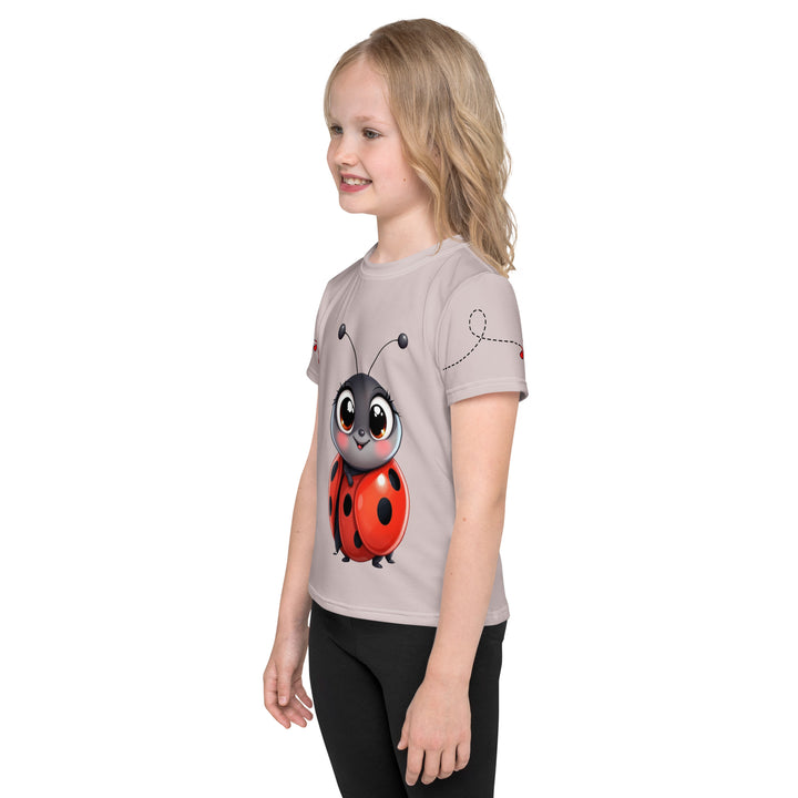  Lovebugs Girls T-shirt, sand-colored background with a smiling female ladybug with big eyes on the front, a happy male ladybug with a heart beside him on the back, and hearts with connecting lines on both sleeves, left side view on model