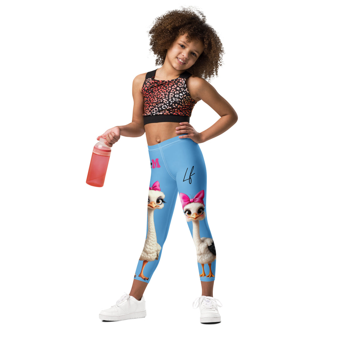 Mama & Me Ostrich Girls Leggings, sky blue background with a large white mother ostrich wearing a pink bow on her head on one leg, "MOM" text in black and pink above, and a smaller white daughter ostrich with black wings and a pink bow on her head on the other leg, relaxed front pose on model
