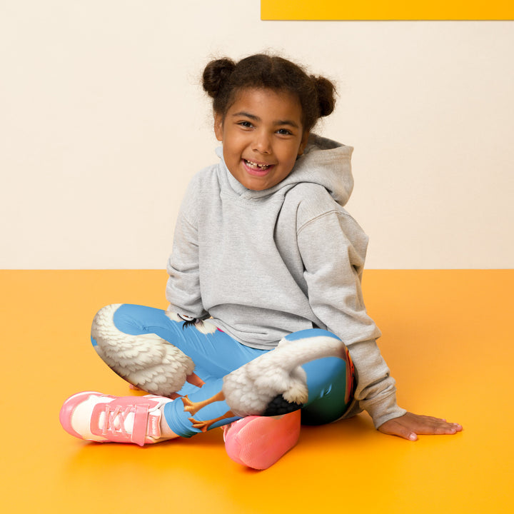  Mama & Me Ostrich Girls Leggings, sky blue background with a large white mother ostrich wearing a pink bow on her head on one leg, "MOM" text in black and pink above, and a smaller white daughter ostrich with black wings and a pink bow on her head on the other leg, seated pose on model