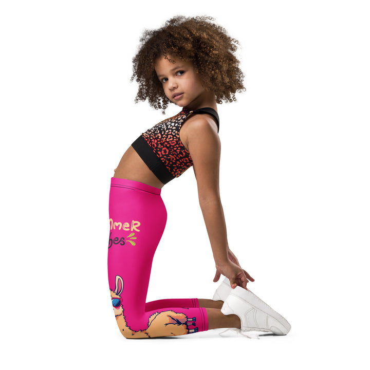  Palma Llama Girls Leggings, pink background with a palm tree wearing sunglasses and holding a cocktail on one leg, and a llama with sunglasses and "SUMMER VIBES" text above on the other leg, designs covering almost the full length of each leg, left side view kneeling on model