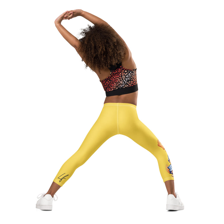 Puppy & Bones Girls Leggings, yellow background with a golden retriever puppy wearing a blue and white striped outfit and a matching blue and white bow on the head on one leg, and blue paw prints and blue bones running down the other leg, back angle with relaxed pose on model