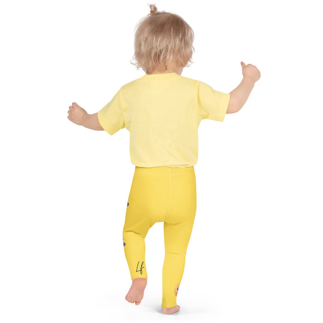 Puppy & Bones Girls Leggings, yellow background with a golden retriever puppy wearing a blue and white striped outfit and a matching blue and white bow on the head on one leg, and blue paw prints and blue bones running down the other leg, back pose on model