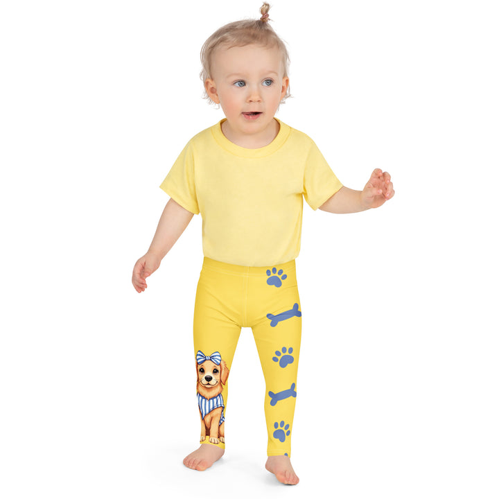 Puppy & Bones Girls Leggings, yellow background with a golden retriever puppy wearing a blue and white striped outfit and a matching blue and white bow on the head on one leg, and blue paw prints and blue bones running down the other leg, front close-up view on model