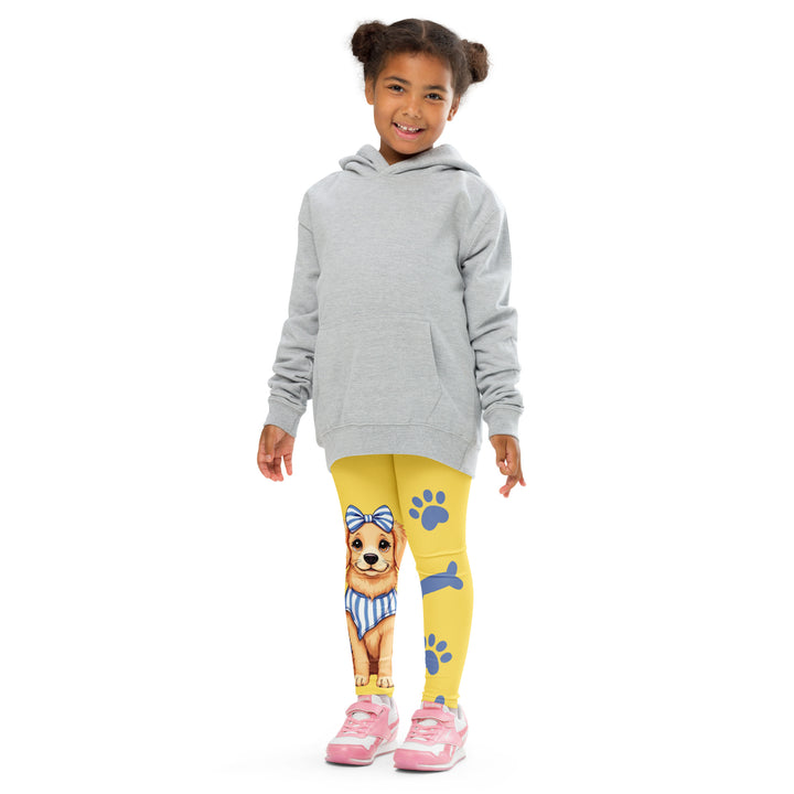 Puppy & Bones Girls Leggings, yellow background with a golden retriever puppy wearing a blue and white striped outfit and a matching blue and white bow on the head on one leg, and blue paw prints and blue bones running down the other leg, front pose with arms at sides on model